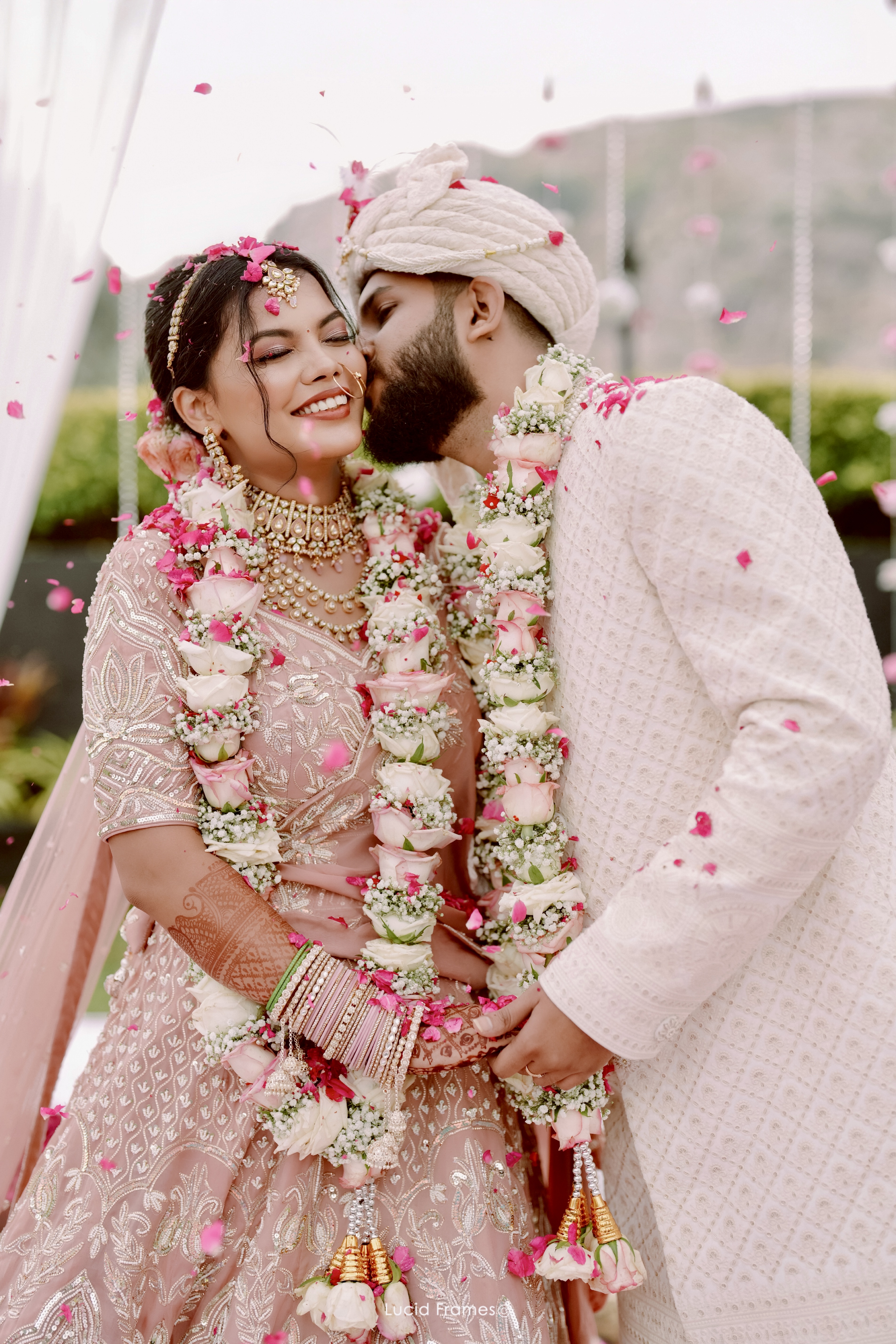 Bride laughing with her partner beneath white ceremonial flowers