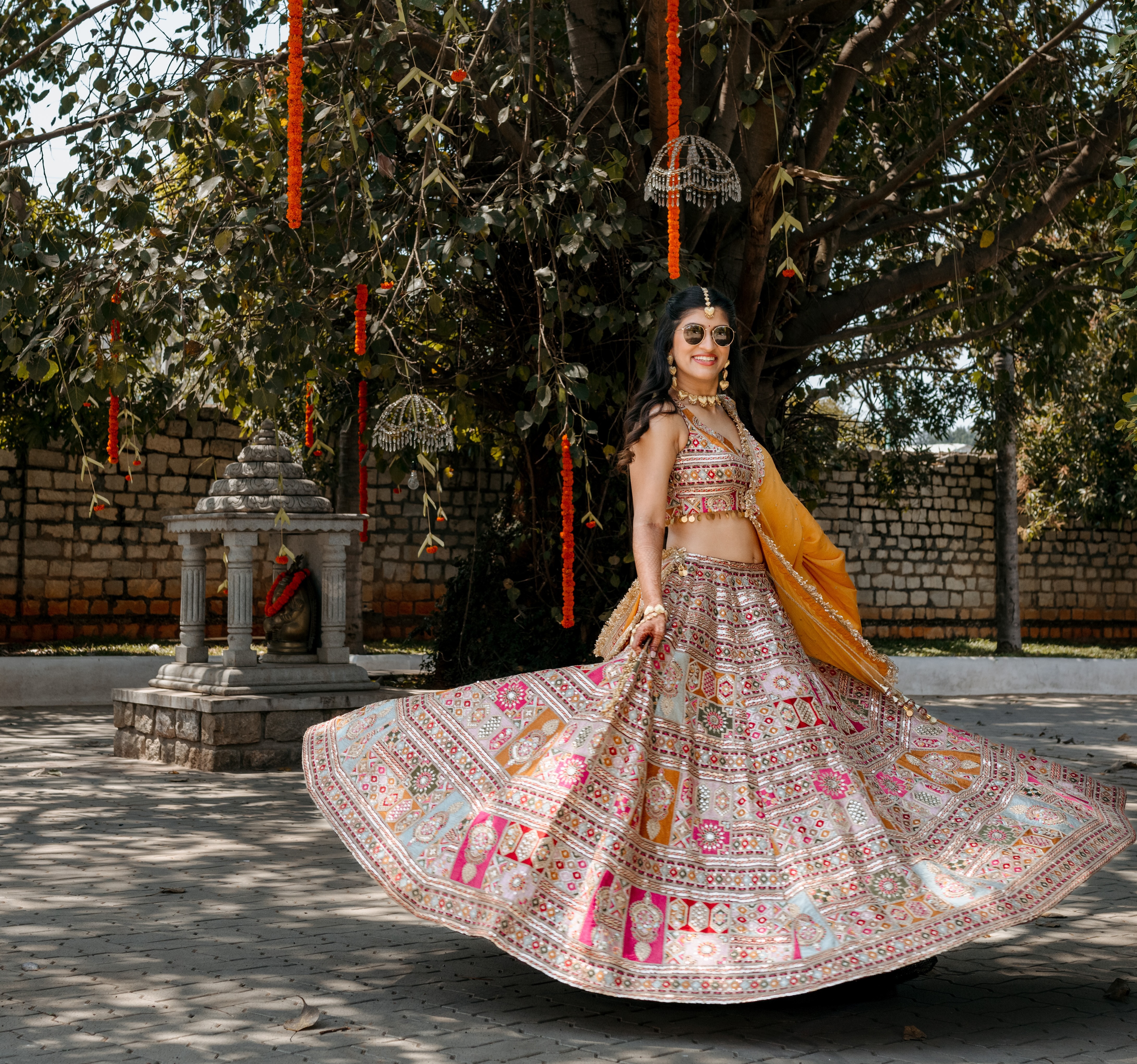 Bride beneath marigolds wearing colourful traditional dress